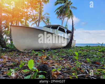 Damaged ship stuck on beach on blue sea and sky background Stock Photo