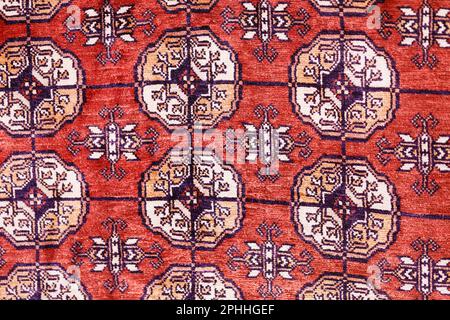 Colorful handmade silk carpet with pattern in red tones, traditional uzbekistan style. Close up. Stock Photo