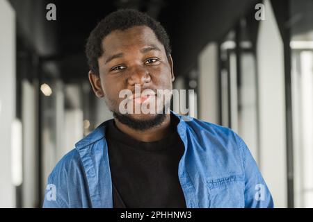 Portrait of happy African American small business owner. Millennial black male team leader smiling, looking at camera, employees working in modern Stock Photo