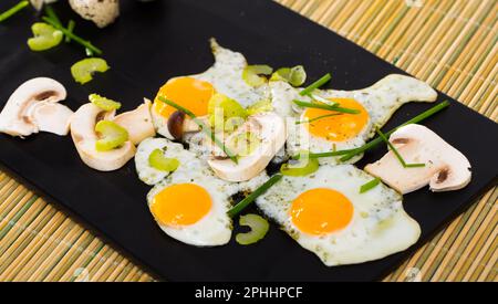 Fried quail eggs with champignons Stock Photo