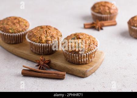 Homemade freshly baked pumpkin muffins with oatmeal and nuts on a beige textured background Stock Photo