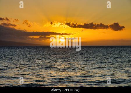 Bright sun setting between clouds at the ocean horizon. Stock Photo