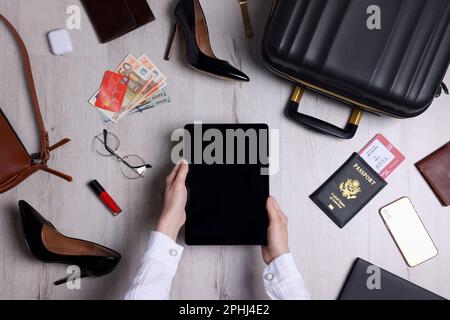 Woman preparing essentials for business trip on wooden floor, top view Stock Photo