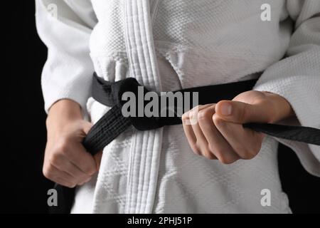 Man in keikogi with black belt on dark background, closeup. Martial arts uniform Stock Photo