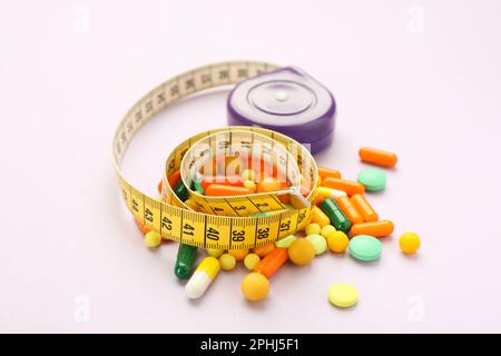 Many different weight loss pills and measuring tape on violet background Stock Photo