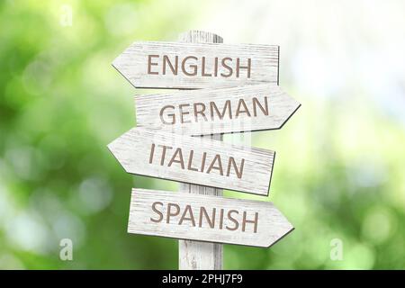 Wooden signpost with names of different languages outdoors Stock Photo