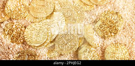 A Buried Pirate Treasure Gold Coins in the Sand on a Beach Stock Photo