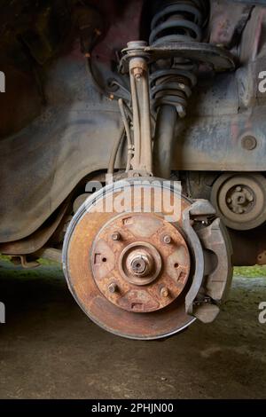 old and rusty car disk brake and caliper with steering knuckle and suspension without wheel, car care and safety concept, car maintenance in selective Stock Photo