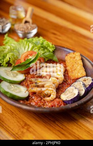 Deep fried shrimps or prawn with spicy chili sauce or sambal and eggplant in pottery plate on wooden table Stock Photo