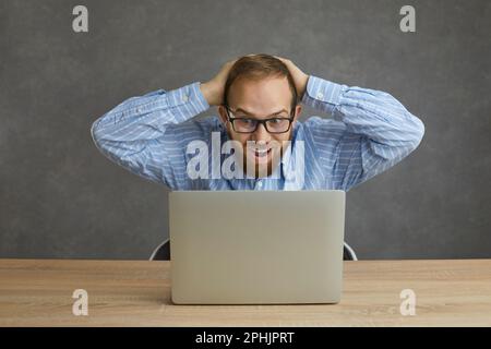 Happy shocked caucasian man impressed scream looking at laptop studio shot Stock Photo