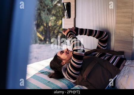 Young woman relaxing using phone in camper van Stock Photo