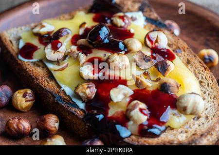 Bread toast with butter, roasted hazelnuts, honey, berry jam on plate ...