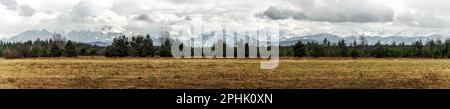 Panoramic view on Tatra Mountains, Poland seen from further. Snow-covered peaks of the rocky mountains and cloudy sky in the time of early spring. Nat Stock Photo