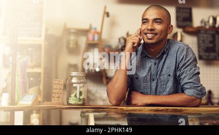 He was born to be an entrepreneur. a young entrepreneur using a phone in his store. Stock Photo