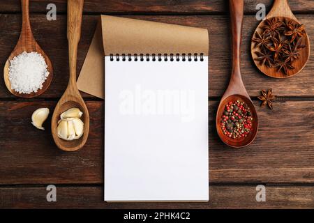 Notebook and different spices on wooden table, flat lay with space for text. Cooking Classes Stock Photo