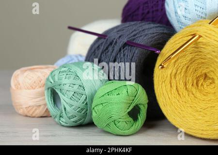 Clews of colorful knitting threads and crochet hooks on white wooden table, closeup Stock Photo