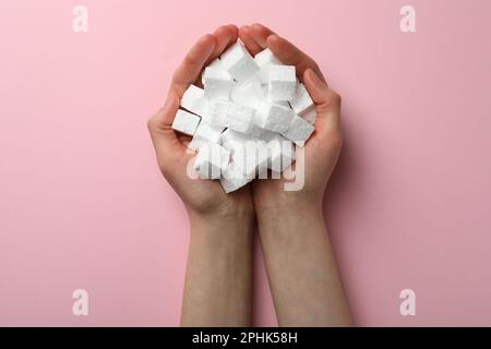 Woman with handful of styrofoam cubes on pink background, top view Stock Photo