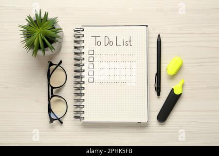 Flat lay composition with unfilled To Do list in notepad and houseplant on wooden table Stock Photo