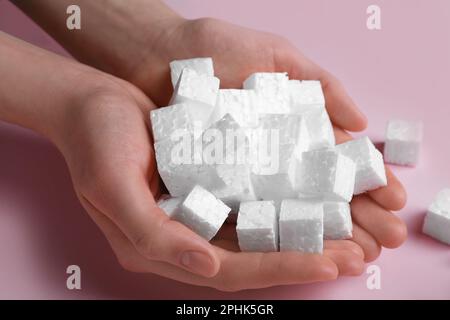 Woman with handful of styrofoam cubes on pink background, closeup Stock Photo