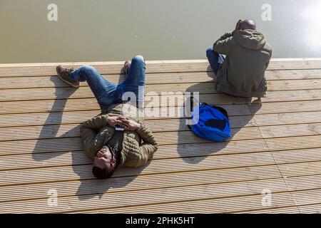 Two young men sunbathing on the banks of the canal in Brussels. Stock Photo