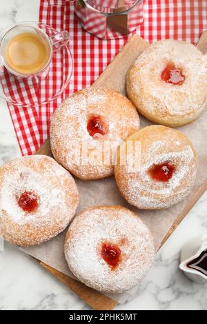 Delicious jam donuts served with coffee on white marble table, flat lay Stock Photo