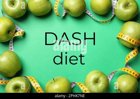 DASH diet to stop hypertension. Ripe apples and measuring tape on green background, flat lay Stock Photo
