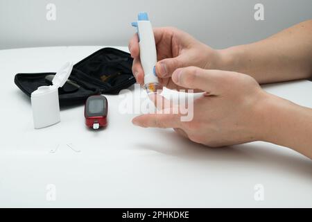 Closeup of young man using lancelet on finger in bathroom Stock Photo