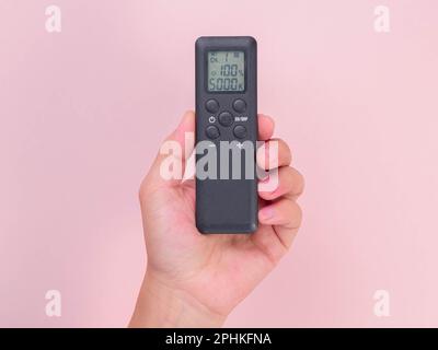 Hand holding remote control isolated on pink background. Remote control in human hand. Stock Photo