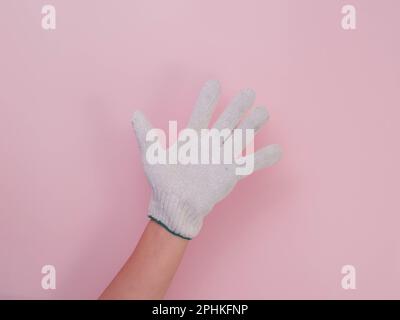 Hands in white knitted gloves isolated on pink background. Female hands with cotton gloves. Stock Photo