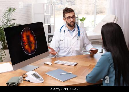 Neurologist consulting young patient at table in clinic Stock Photo