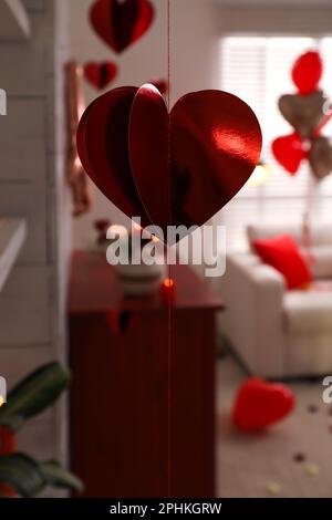 Cozy living room decorated for Valentine's Day, focus on red foil heart Stock Photo