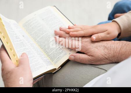 Boy and his godparent reading Bible together indoors, closeup Stock Photo