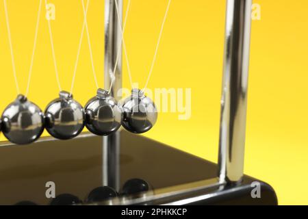 Newton's cradle on yellow background, closeup. Physics law of energy conservation Stock Photo