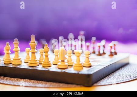 chess board with wooden chess pieces on a purple background. Board game start Stock Photo
