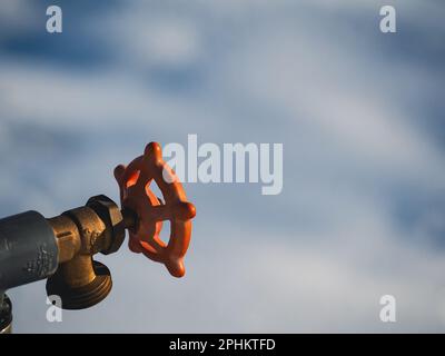 A close-up shot of an orange water meter with a nozzle and handle Stock Photo