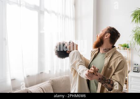 Cheerful multiethnic couple dancing while having fun in kitchen at home,stock image Stock Photo
