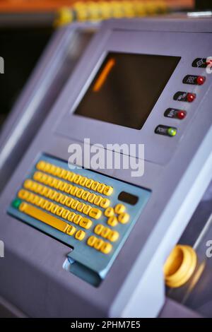 Built-in color keyboard with yellow mechanical buttons for the computer of a large industrial knitting machine with a built-in monitor next to it Stock Photo