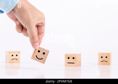 Businessman chooses a smile emoticon icons face happy symbol on wooden block , Services and Customer satisfaction survey concept Stock Photo