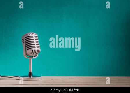 Retro microphone on wooden table with green wall background Stock Photo