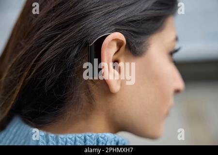 Close Up Of Young Woman Wearing Behind The Ear Hearing Device Or Aid Stock Photo