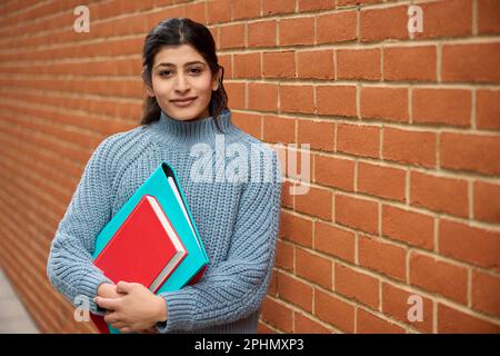 Portrait Of Smiling Female College Or University Student Outside Campus Building With Books Stock Photo