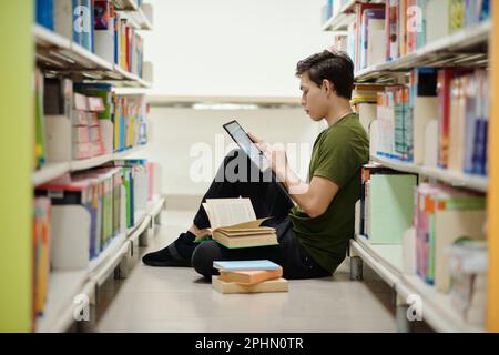 College student sitting on library floor and working on project Stock Photo