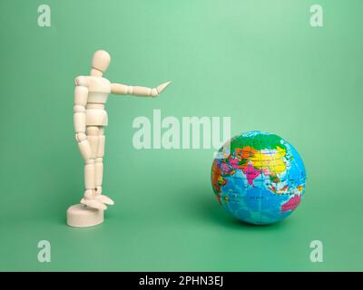 Wooden mannequin and earth globe on a green background Stock Photo