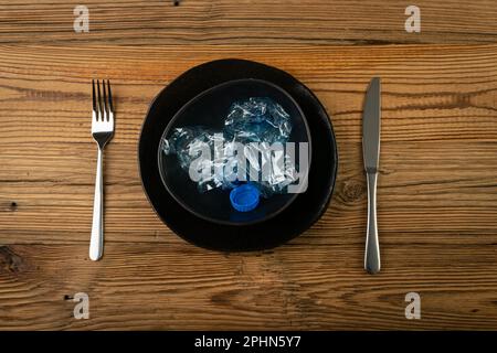 Eat Plastic, Blue Empty Plastic Bottle on Plate, Crumpled Plastic Bottle, Global Pollution Concept, Squashed Water Pet Bottles on Wood Background Stock Photo