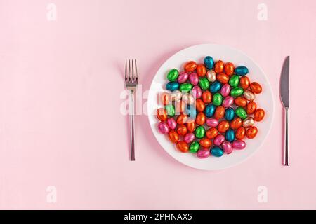 Happy Easter. Table setting for Easter holiday. Easter chocolate eggs and cutlery on pink background. Top view, flat lay Stock Photo