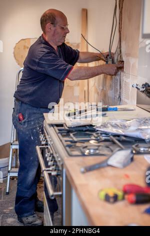 Kitchen Fitters: Electrical Installation.An electrician connecting cables into wall chasing for a new plug socket. From a series of related images. Stock Photo