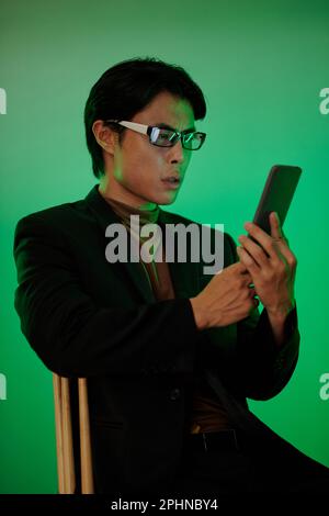 Shocked Asian man reading text message on smartphone Stock Photo