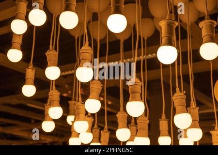 Hanging LED Light Bulbs on Blurred Background, Warm Energy Saving Lamp, Yellow Light of Incandescent Lightbulbs Stock Photo