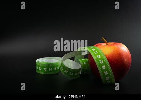 Red Apple and Measuring Tape, Measure Tapes, Metric Tape on Black Background, Health Diet Food, Weight Loss Concept Stock Photo