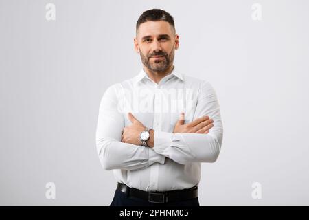 Portrait of handsome middle aged businessman with folded arms standing over grey background and looking at camera Stock Photo